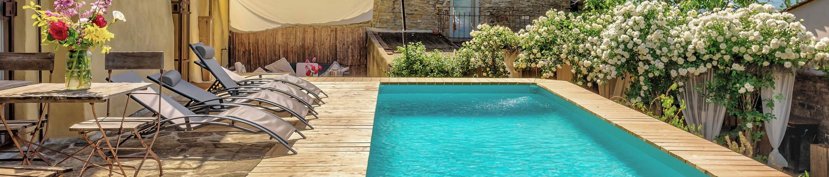 Sonnige Terrasse mit Pool und Liegestühlen an einem Toskana-Ferienhaus