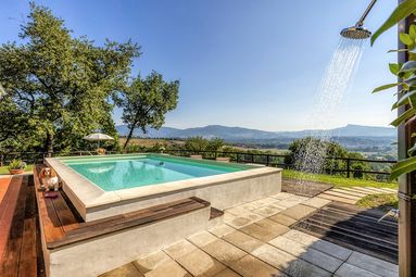 Ferienhaus mit Pool in der Toskana, Gäste entspannen am Pool mit Blick auf die hügelige Landschaft.